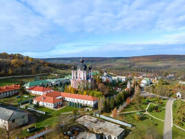 Uitzicht op het Curchi-klooster vanaf de drone. Kerken, andere gebouwen, groene gazons en wandelpaden. Heuvels met in de verte groen. Moldavië