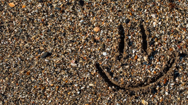 Gratis foto uitzicht op het zand op het strand in de zomer met een emoticon