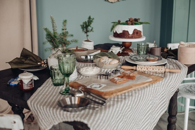 Uitzicht over witte moderne kamer ingericht voor kerstvakantie. Gedecoreerde en verlichte kerstboom, open haard met dennentak, kaarsen en handgeschept papier sterren in open haard.