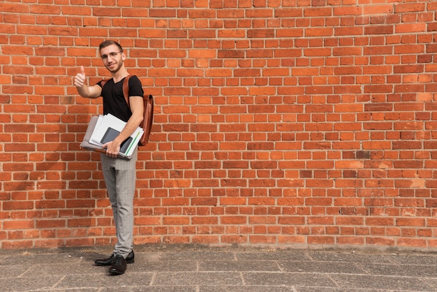 Universitaire student die zich voor een ruimteachtergrond van het bakstenen muurexemplaar bevindt