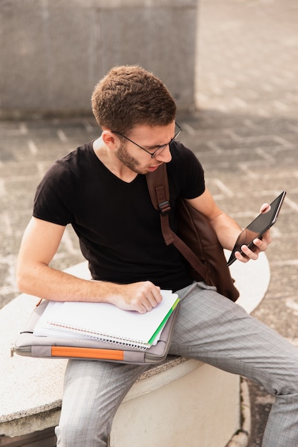 Universitaire studentenzitting op een bank en het bekijken tablet