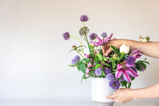 Vaas met verse zomerbloemen in vrouwelijke handen op een witte achtergrond