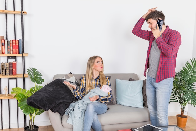 Vader die op telefoon dichtbij moeder met kleine baby spreekt