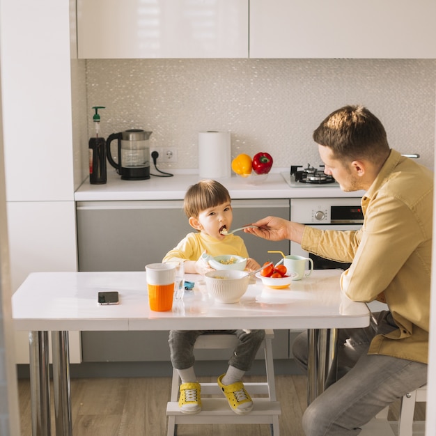 Vader die zijn zoon in de keuken voedt