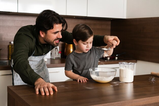 Vader die zoon helpt om deeg te maken