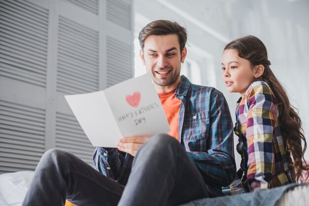 Vader en dochter die dichtbije getrokken kaart op vadersdag bekijken