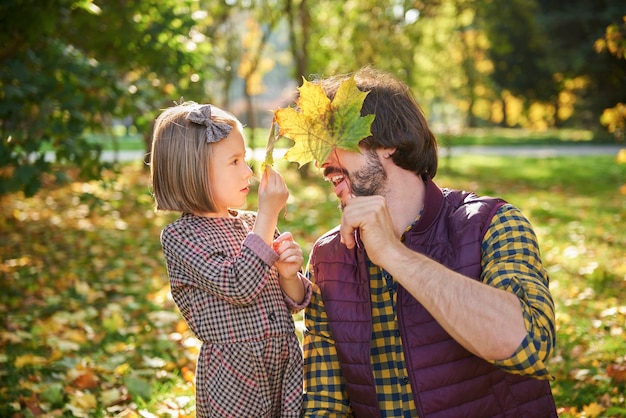 Gratis foto vader en dochter herfstbladeren plukken