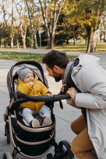 Gratis foto vader en kind in kinderwagen buitenshuis