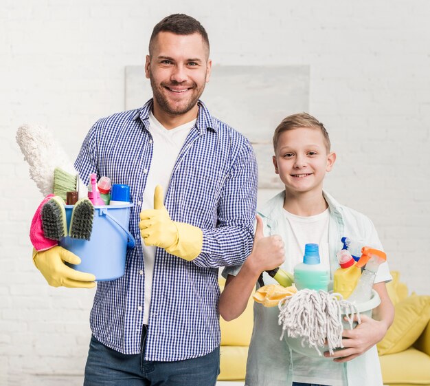 Vader en zoon die duimen opgeven terwijl het houden van schoonmakende producten