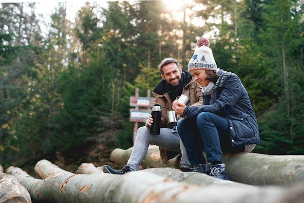 Vader en zoon die hete thee drinken in het herfstbos