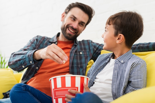 Vader en zoon die popcorn eten en elkaar bekijken