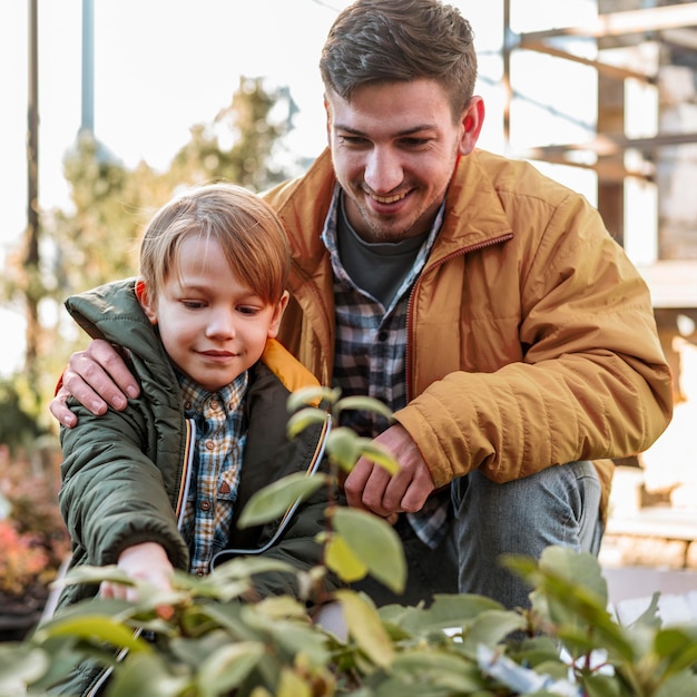 Gratis foto vader en zoon die samen een plant plukken