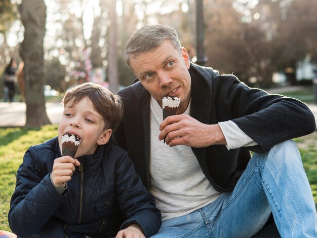 Vader en zoon eten van ijs in het park