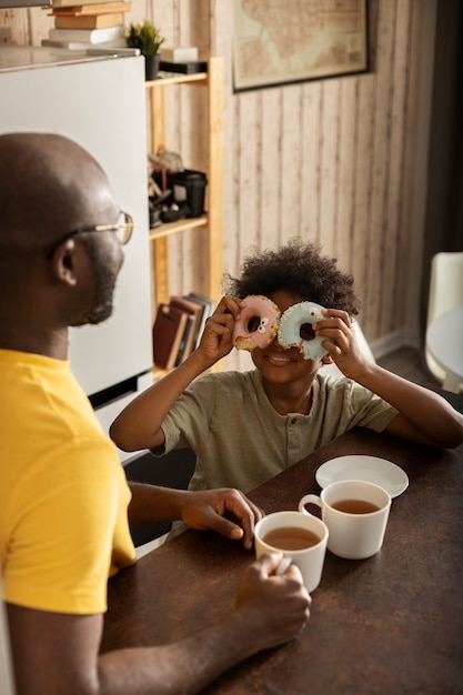 Gratis foto vader en zoon hebben samen donuts in de keuken