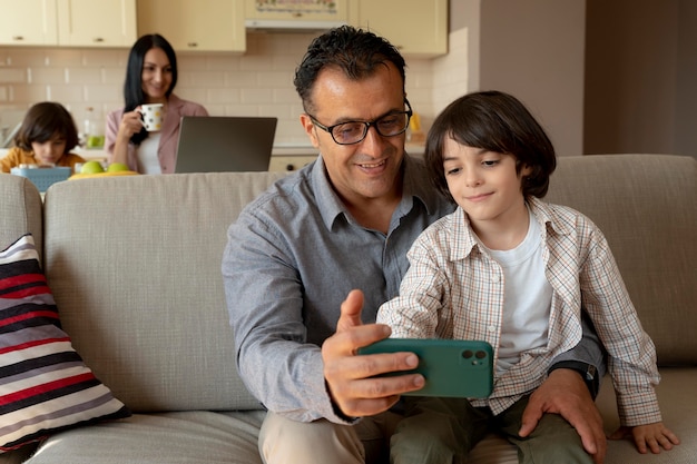 Gratis foto vader en zoon kijken naar een smartphone thuis