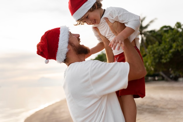 Vader en zoon op het strand met kerstmutsen