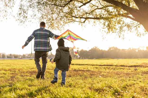 Gratis foto vader en zoon spelen met een vlieger lang zicht