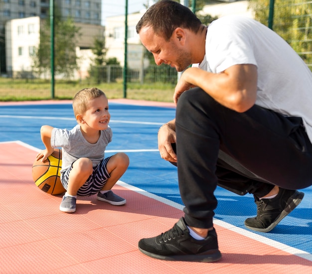 Gratis foto vader en zoon spelen samen op het basketbalveld