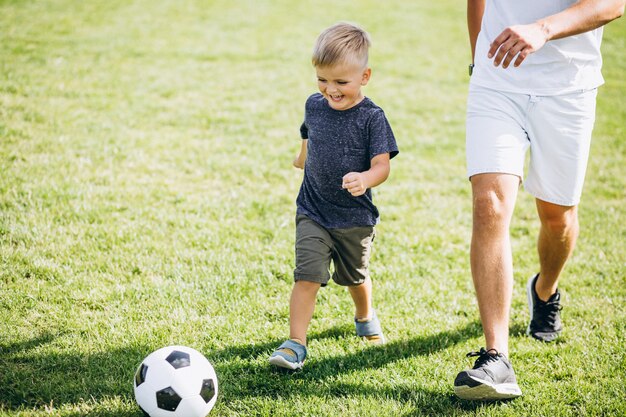 Vader en zoon voetballen bij het veld