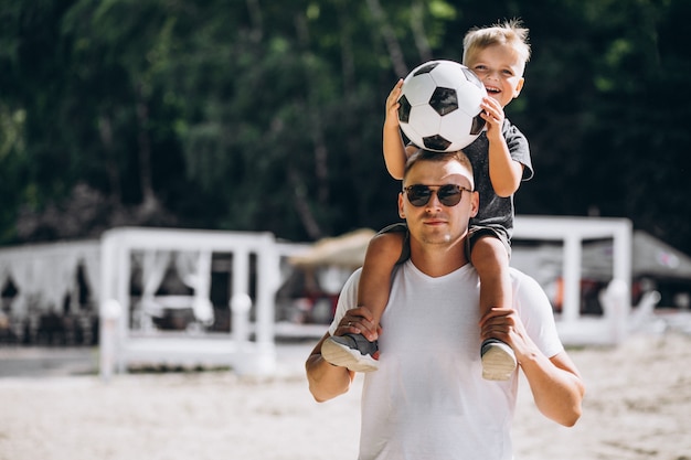 Vader en zoon voetballen op het strand