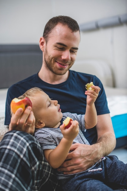 Vader glimlachend naar zijn zoon tijdens het eten van fruit