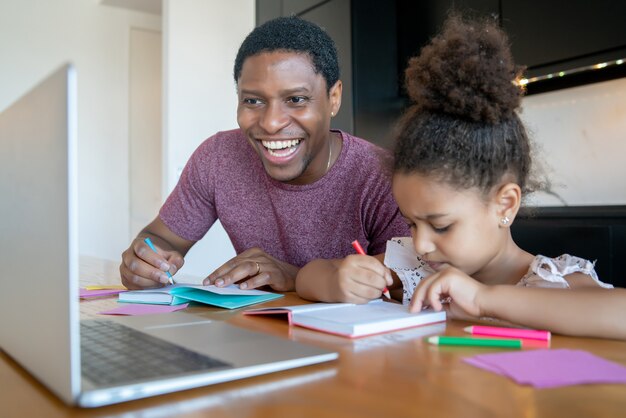 Vader helpt en ondersteunt zijn dochter met online school terwijl ze thuis blijft