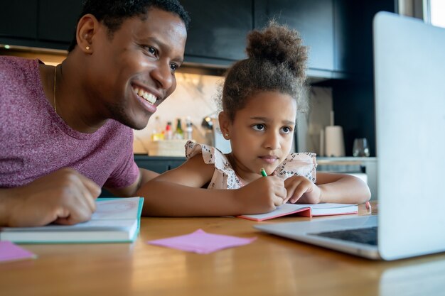 Vader helpt en ondersteunt zijn dochter met online school terwijl ze thuis blijft