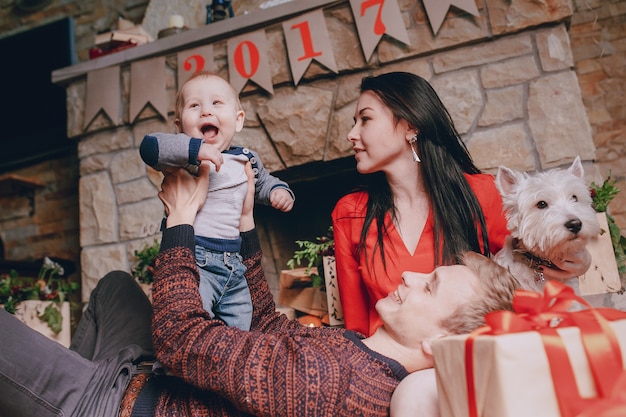 Vader liggend op de vloer te spelen met zijn zoon, terwijl zijn vrouw kijkt en open haard achtergrond