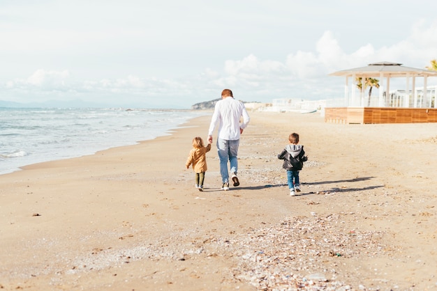 Vader met zonen wandeling langs strand