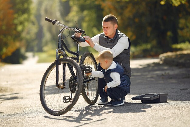 Vader met zoon repareren de fiets in een park