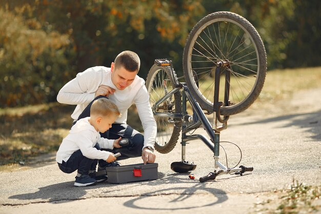 Vader met zoon repareren de fiets in een park