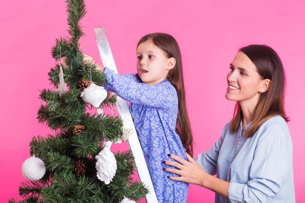 Vakantie familie en kerst concept moeder en dochter kerstboom versieren op roze Premium Foto