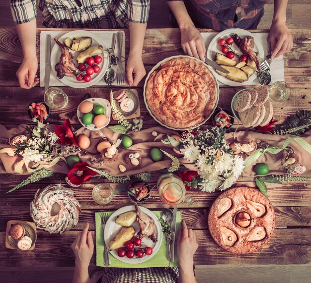 Vakantie vrienden of familie aan de vakantie tafel met konijnenvlees, groenten, taarten, eieren, bovenaanzicht.