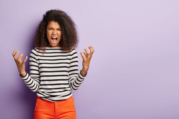 Val me niet lastig! Woedende Afro-vrouw gebaart boos en schreeuwt naar iemand