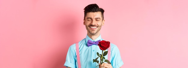 Gratis foto valentijnsdag en romantiekconcept romantische man met rode roos die op date gaat met minnaar die zich in f bevindt