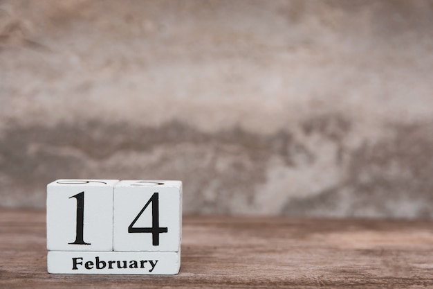 Valentijnsdag met 14 februari. houten witte blokkalender op houten lijstachtergrond met exemplaarruimte