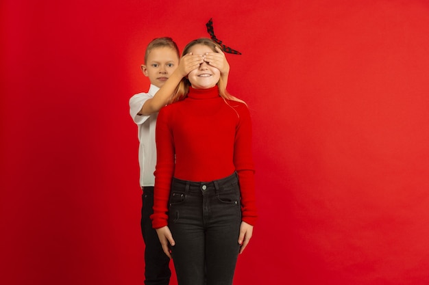 Valentijnsdagviering, gelukkige, schattige blanke kinderen geïsoleerd op rode studio