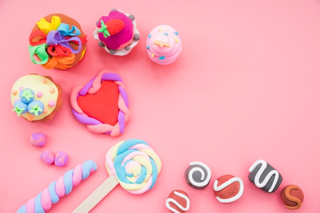 Gratis foto valse handgemaakte koekjes en cake gemaakt met klei op roze achtergrond