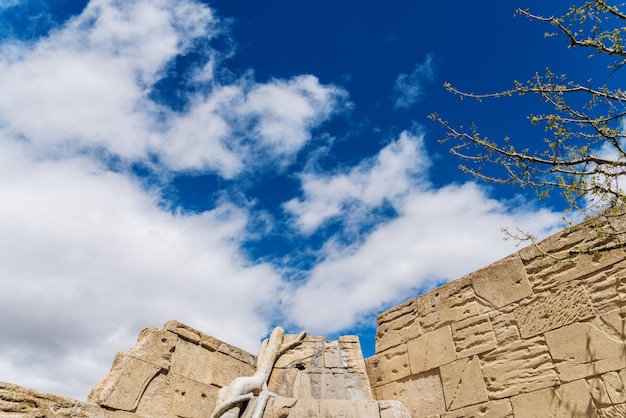 Valse stenen muur bedekt met vegetatie wijnstokken en blauwe lucht met wolken