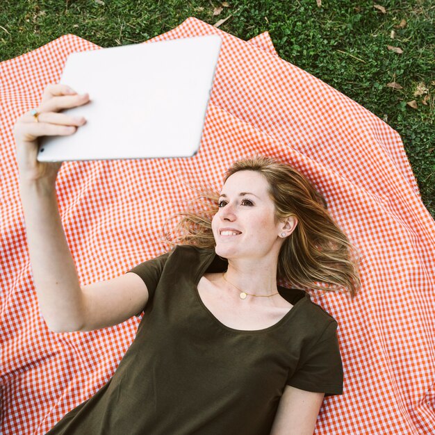 Van bovenaf jonge vrouw met behulp van de tablet op picknick