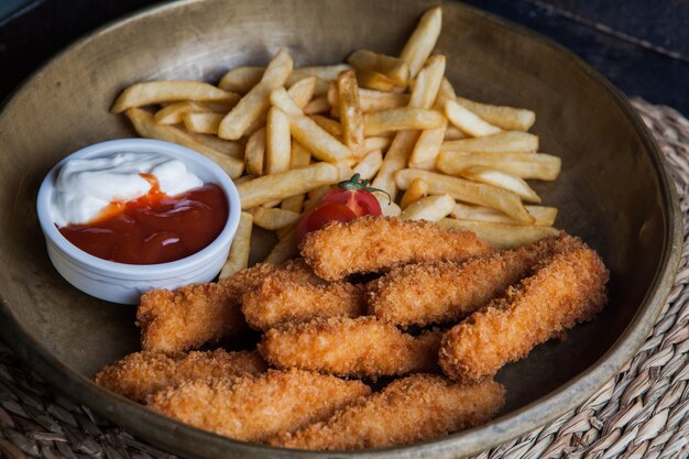 Van bovenaf kipnuggets met patat en sous en tomaat in kleigerechten