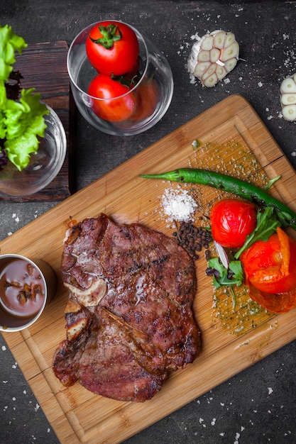 Gratis foto van bovenaf steak met tomaat en papier in steak board