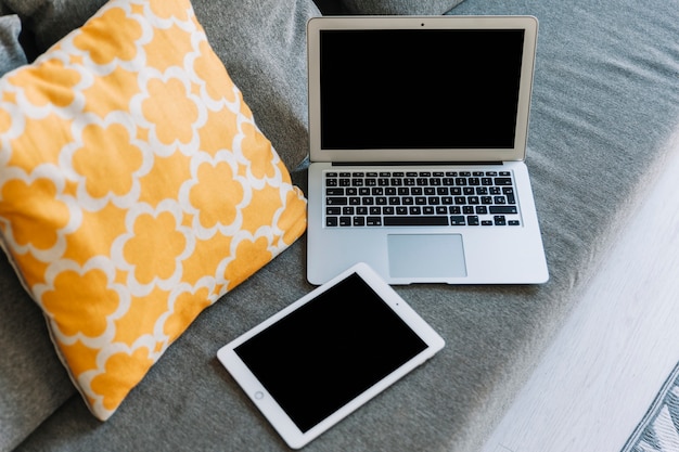 Van bovenaf tablet en laptop op de bank