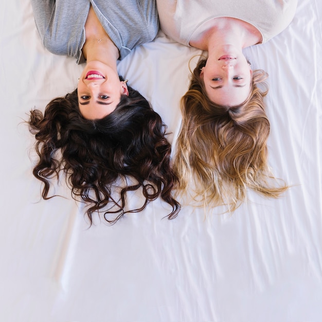 Gratis foto van hierboven vrouwen die op wit blad liggen