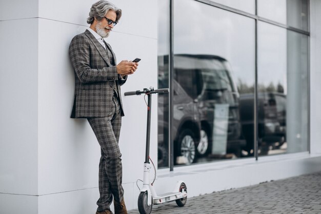 Van middelbare leeftijd zakenman rijden scooter in een stijlvol pak