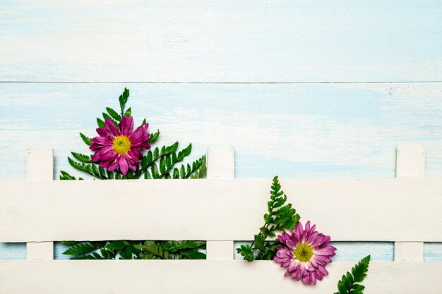 Varens en bloemen achter witte hek