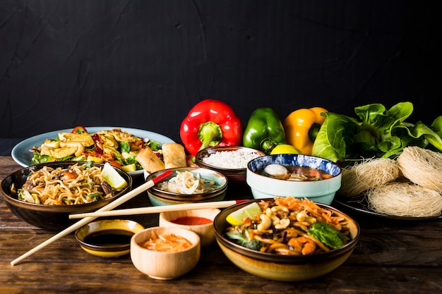 Variatie van Thaise keuken met groene paprika&#39;s en bokchoy op houten bureau tegen zwarte achtergrond