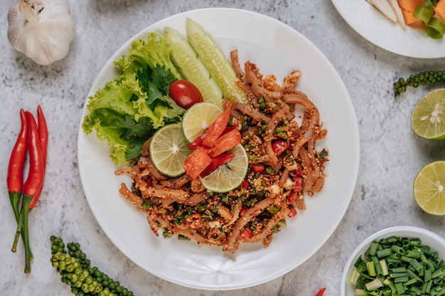 Varkenshuid Larb met wortel, komkommer, limoen, bosui, chili, versgemalen peper en sla.