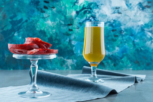 Varkensreuzel op een glazen kom en een glas bier op een stuk stof, op de blauwe tafel.