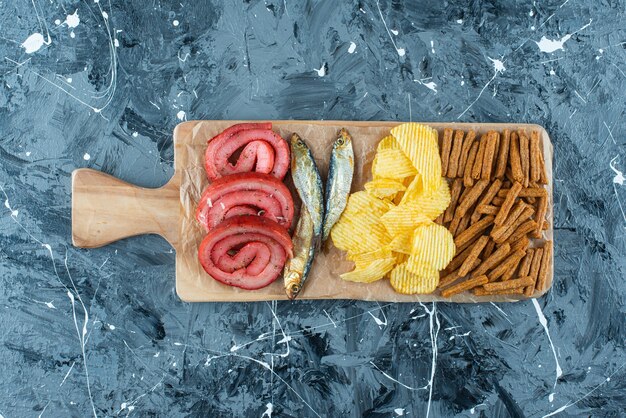 Varkensreuzel, vis, chips en paneermeel op een snijplank, op de blauwe tafel.